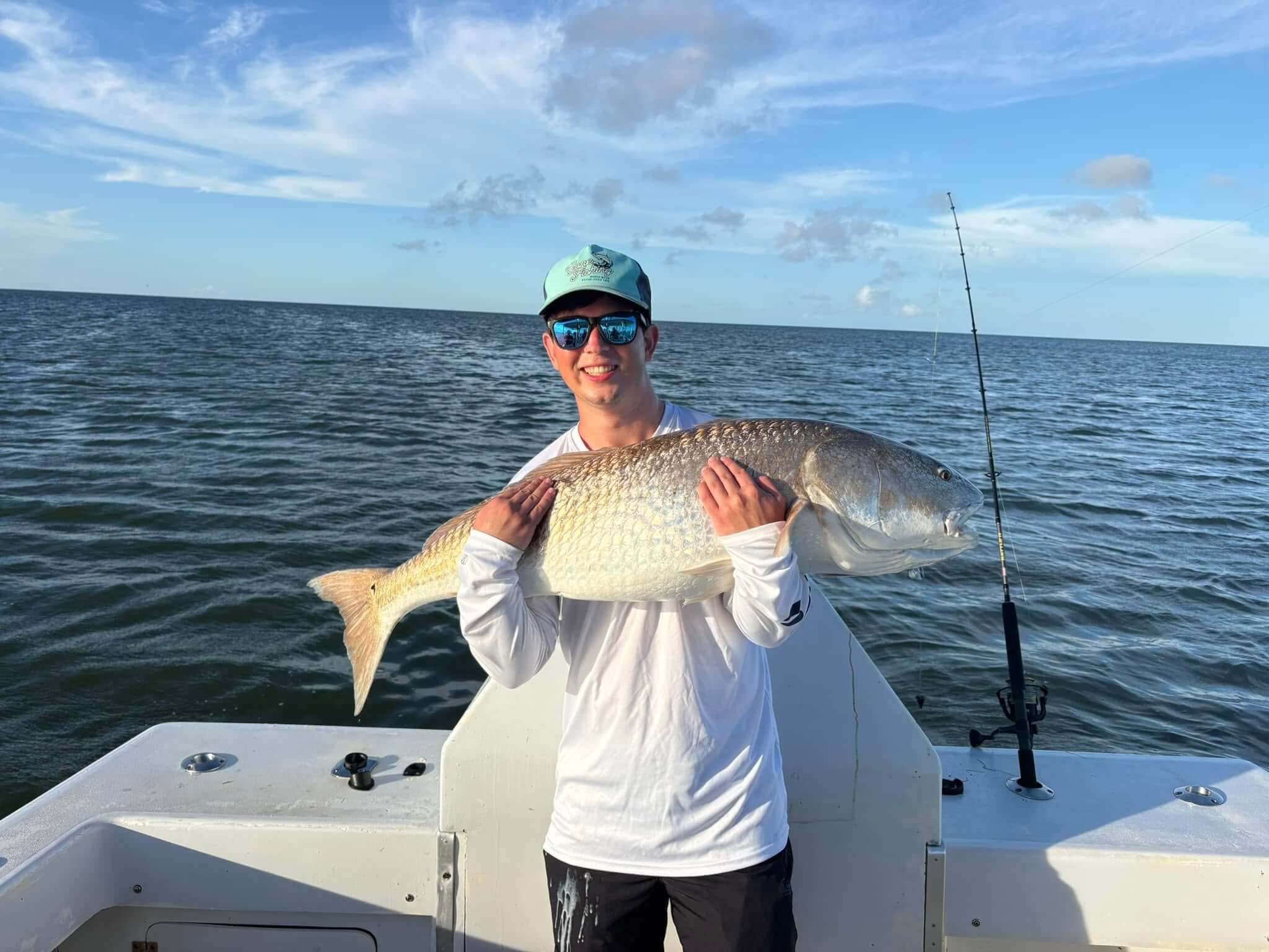 Gecko angler hugs massive red drum he caught.