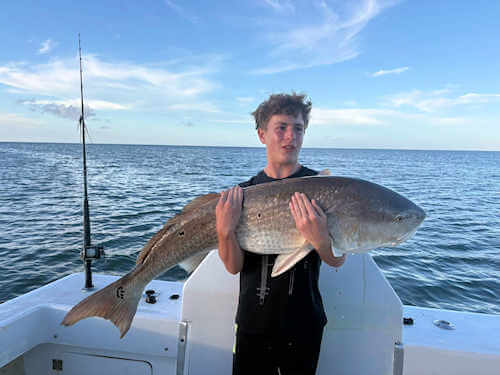 Gecko angler hugs massive red drum he caught.