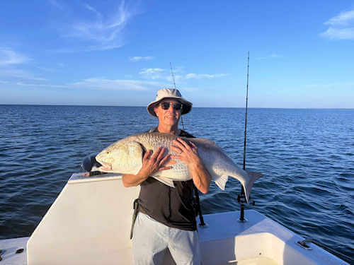 Gecko angler hugs massive red drum he caught.