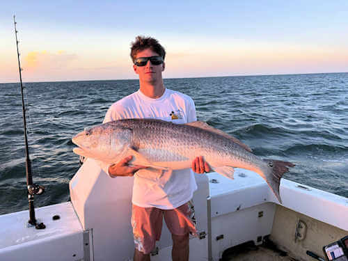Gecko angler hugs massive red drum he caught.