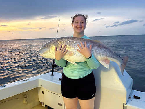 Lady Gecko angler hugs massive red drum she caught.